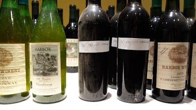 Wine bottles on a table, five in the foreground.