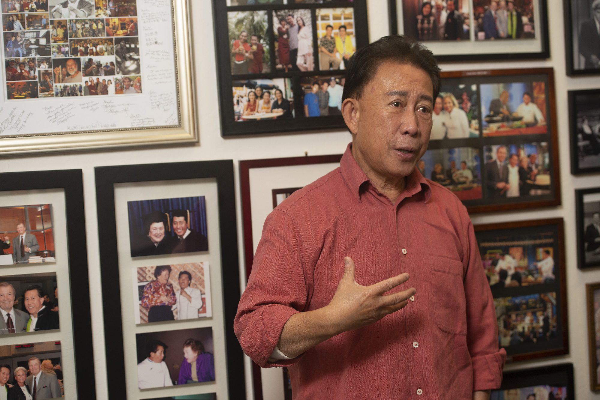 Martin Yan in front of a wall of photos in the offices of Yan Can Cook. Behind him is a series of photos of him with Julia Child.