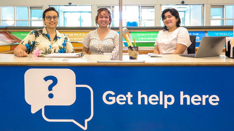 studdents seated behind a sign that partially reads "Get help"