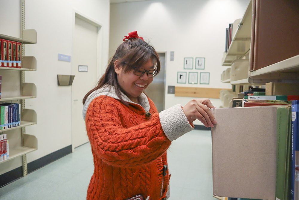 Karis Chun selecting a book from the stacks