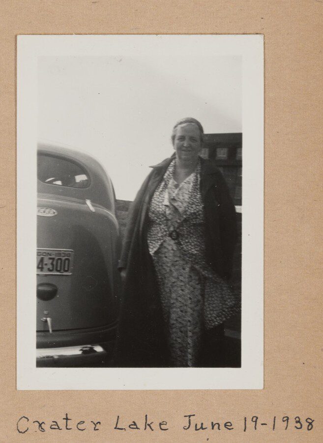 Photo of a woman standing next to a car at Crater Lake.  
