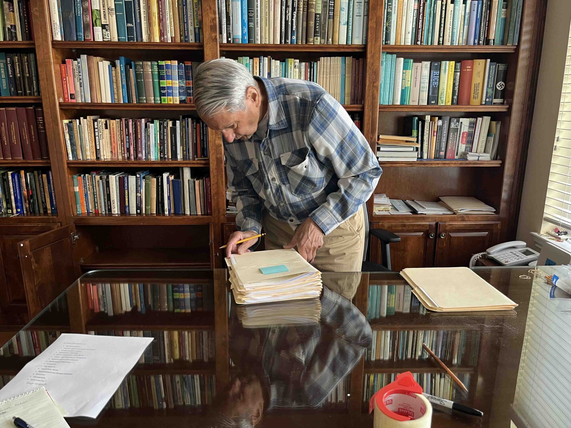 A man prepares folders on a desk in his office