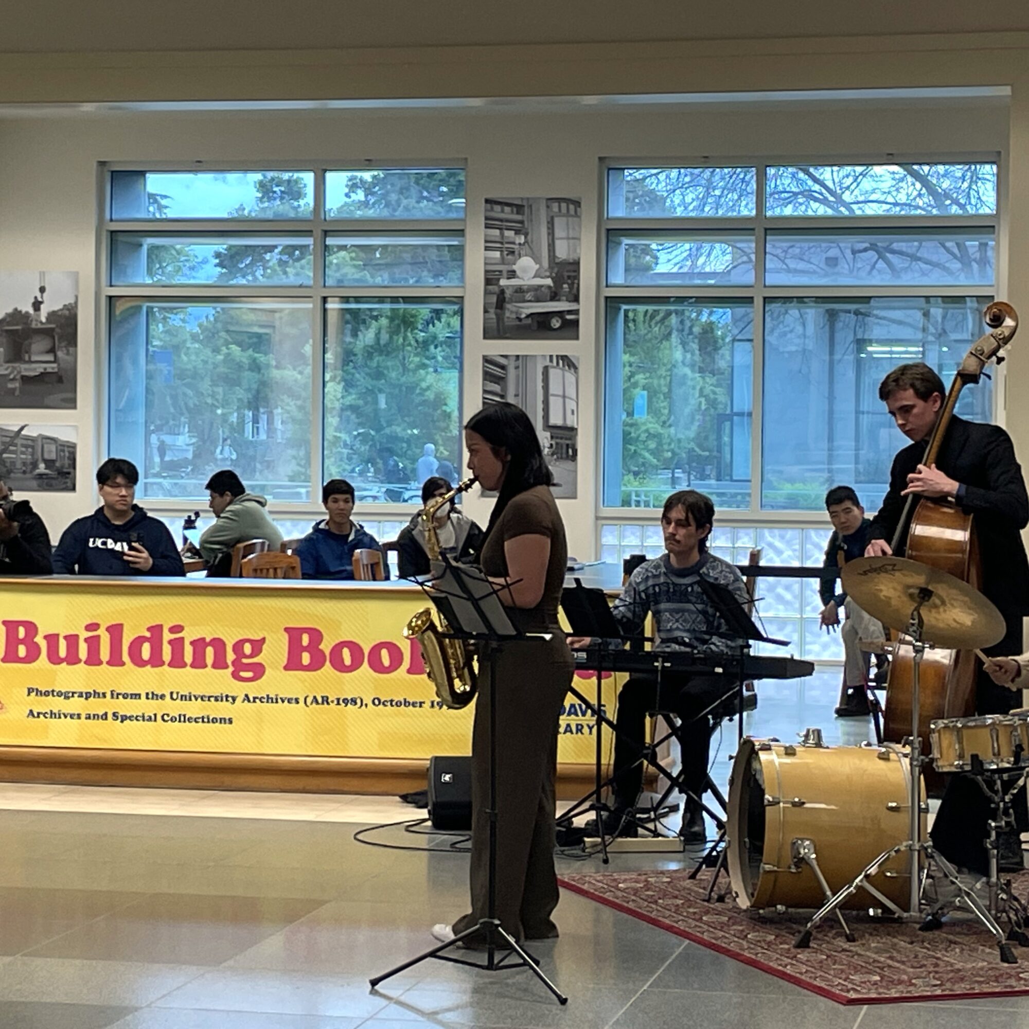 Jazz band performs in the lobby of Shields Library, with an exhibit about the Bookhead sculpture in the background