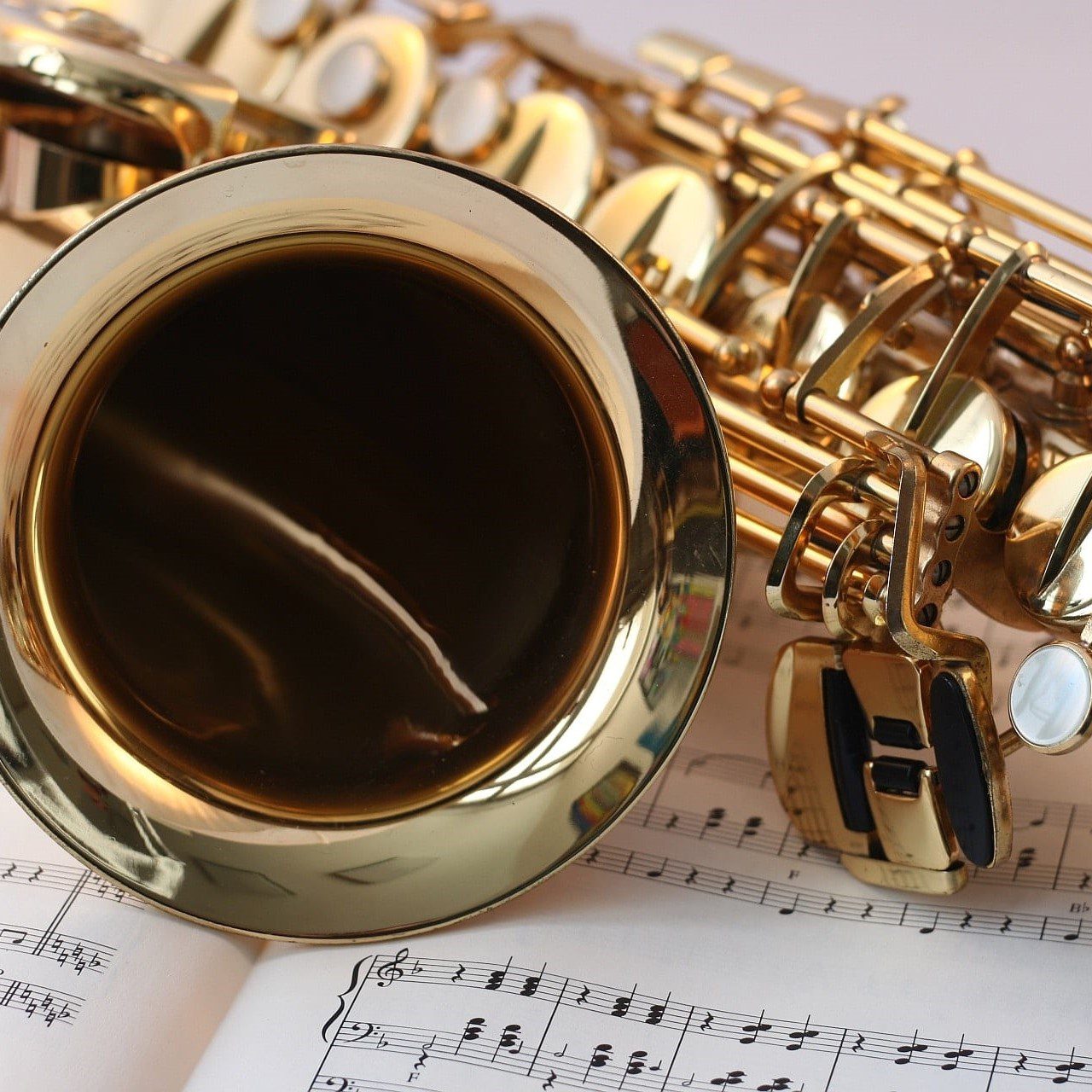 brass saxophone lying on sheet music