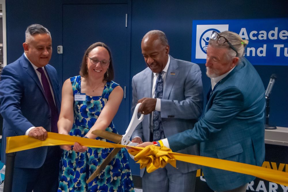 Vice Chancellor Pablo Reguerín, Associate Vice Chancellor Sara Hawkes, and University Librarian and Vice Provost of Digital Scholarship Bill Garrity together hold up the ceremonial gold ribbon while Chancellor May cuts it.