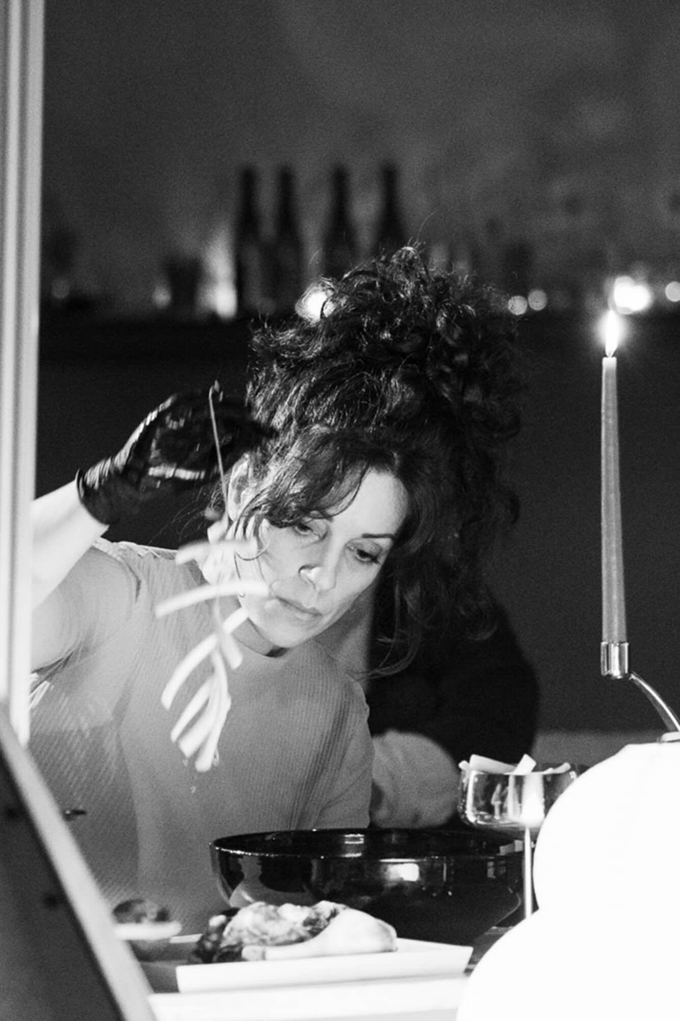 Culinary artist Heidi Ross lifts a string of food over a bowl as part of a performance practice.