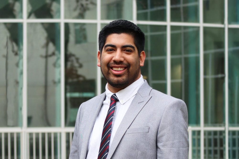 Portrait of Daniel Castaneda with the glass windows of Shields Library in the background