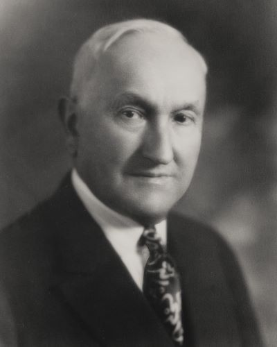 Black-and-white headshot of Georges de Latour wearing a suit jacket and tie