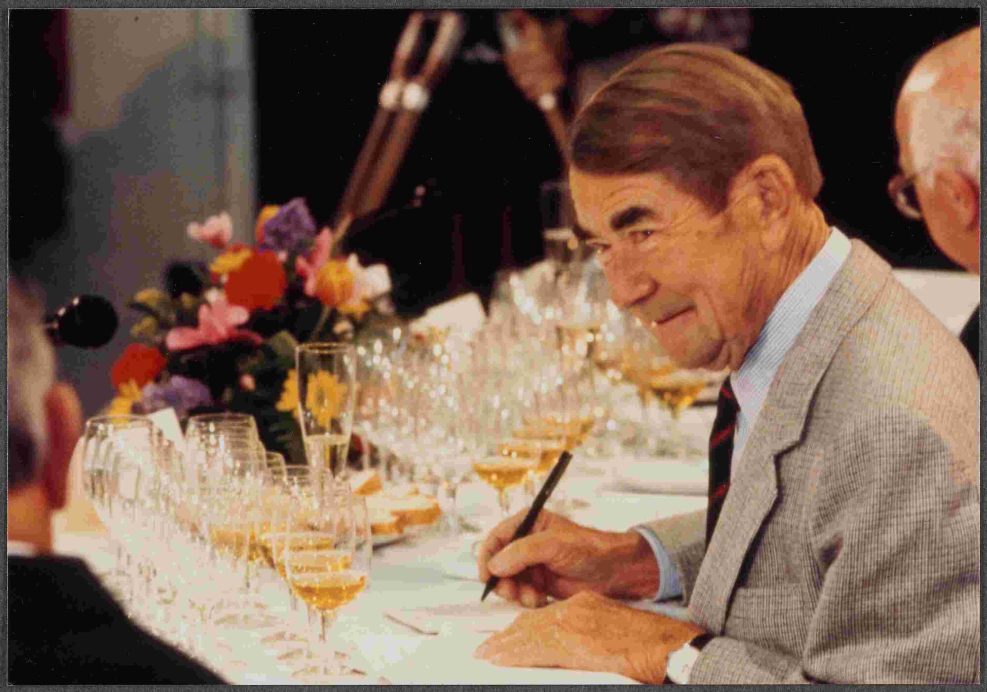 Andre Tchelistcheff judging wine with several wine glasses on a table in front of him