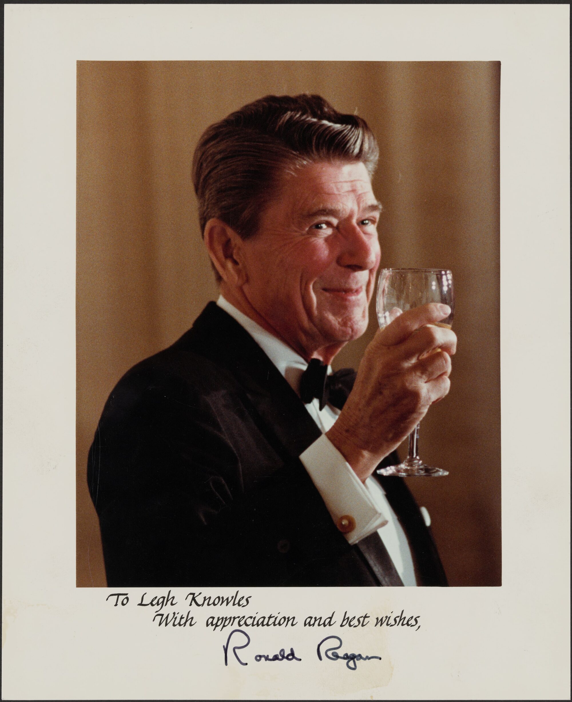 Signed photograph of Ronald Reagan toasting with glass in hand and smiling