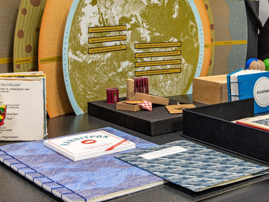 A variety of special collections on a table, including folders, bound albums, wine corks.