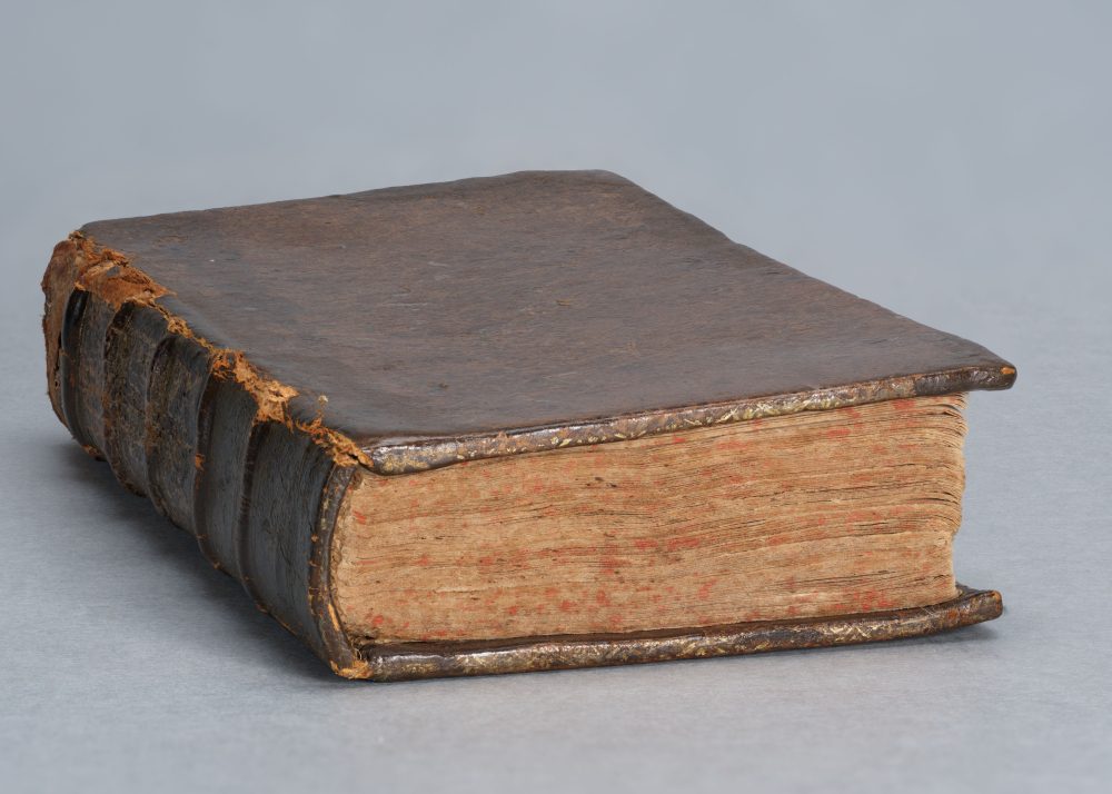 An antique leather-bound book with a brown cover, worn thin in places on the binding