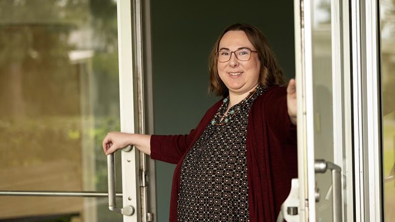 Katie Healey standing in entrance holding door open