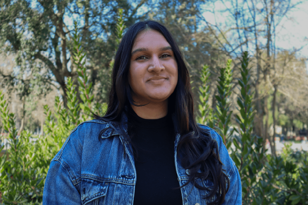 Portrait of 2026 Grad Prize Winner Safa Uraizee with shrubs and trees in background