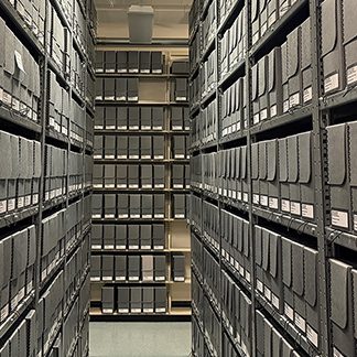 Aisle with shelving. The shelves have many gray boxes on them.