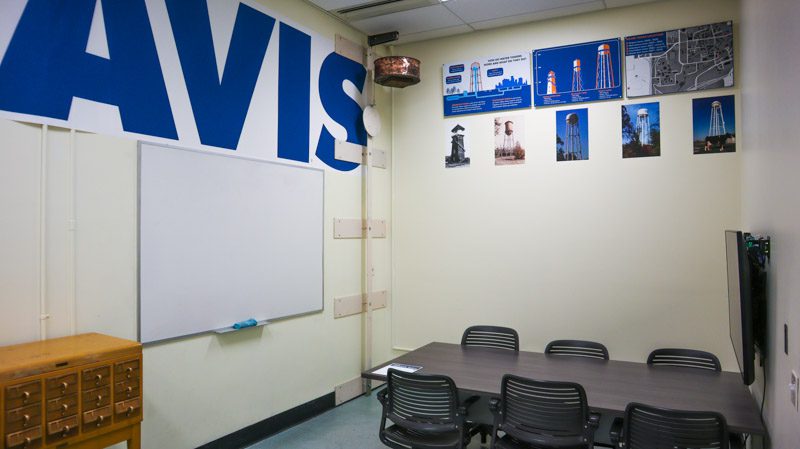 onference table and chairs below a large blue 'UC Davis' wall mural, with a whiteboard and photos of the campus water tower.