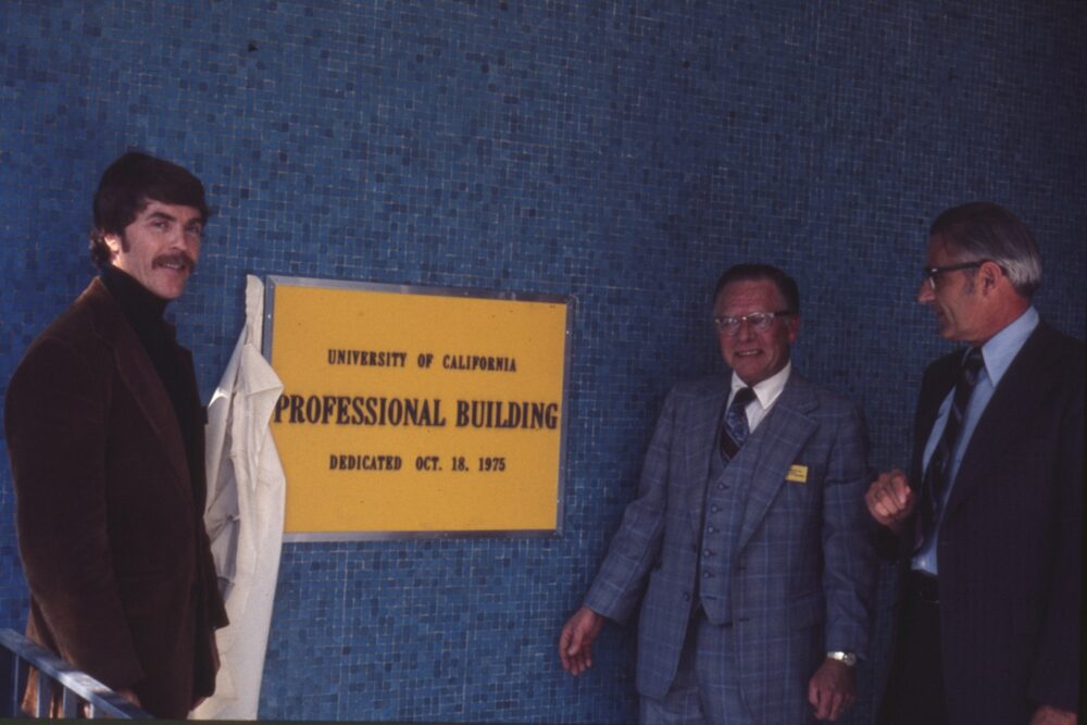 Dean Tupper (center), Chancellor Meyer, and an unidentified person, standing next to a dedication plaque of the Professional Building at the UCDMC in Sacramento